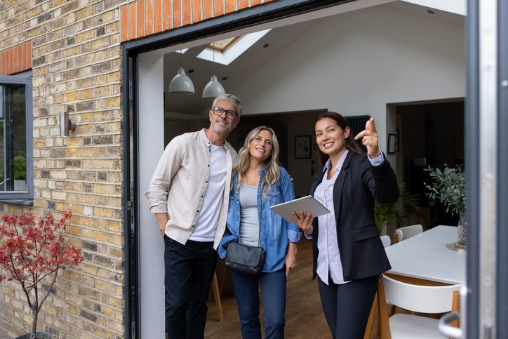 Agent immobilier montrant une maison à vendre à un couple